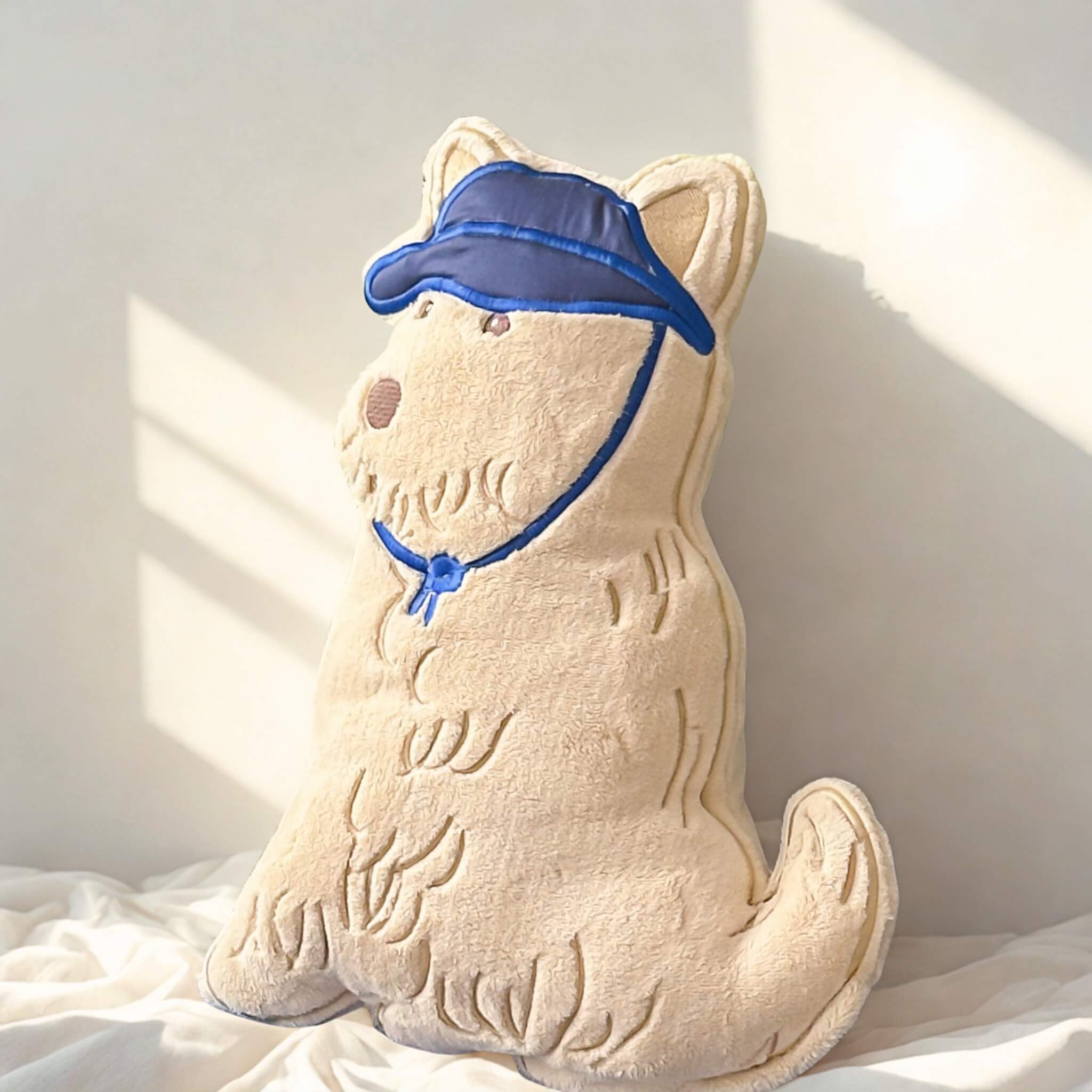 Dog-shaped cushion with a blue cap  on bed