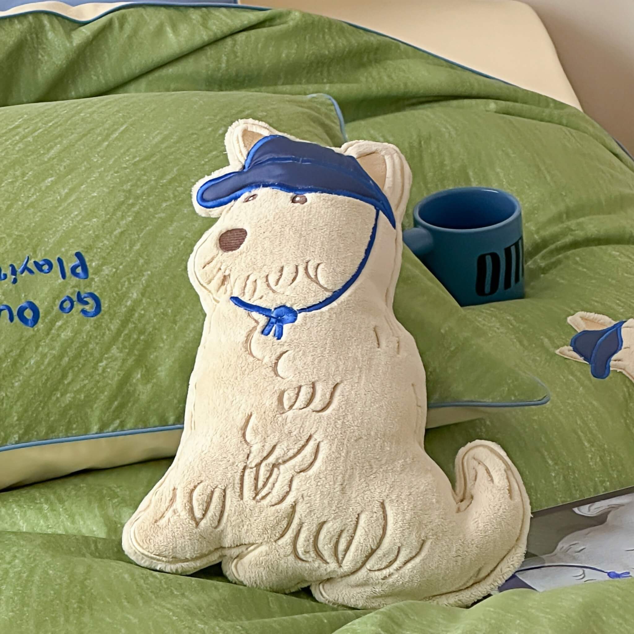Dog-shaped cushion with a blue cap on a green bedding