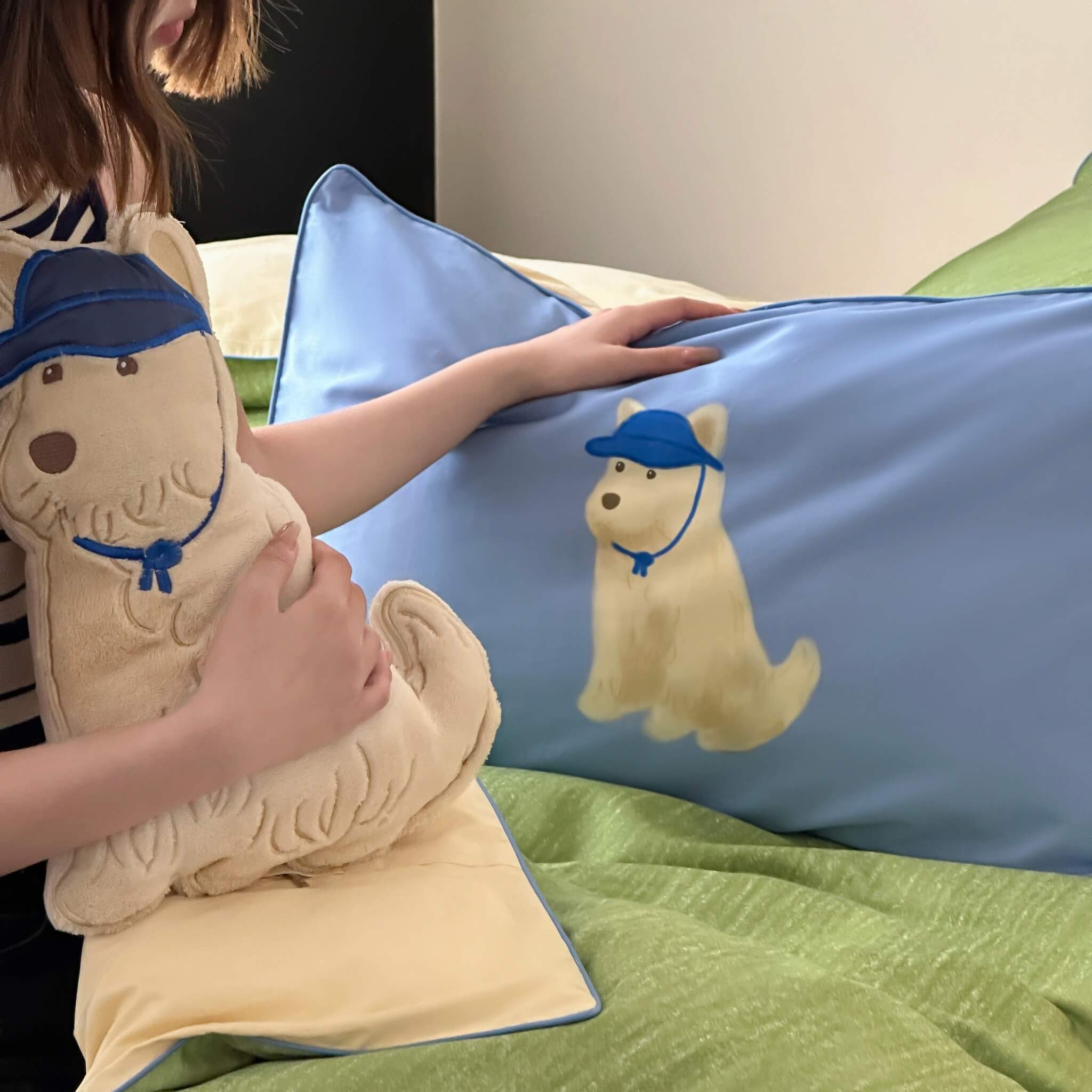 A lady aholding dog-shaped cushion with a pillow featuring a dog design on a bed.